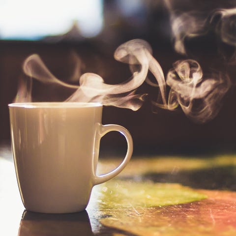 A steaming cup of coffee sits on a table.