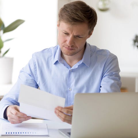 Man holding document with laptop in front of him