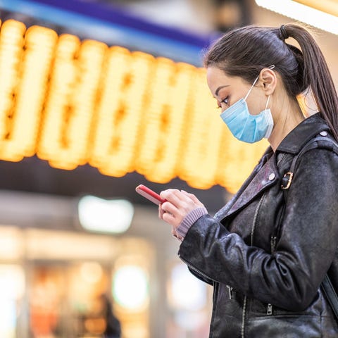 Woman in protective mask using a smartphone.