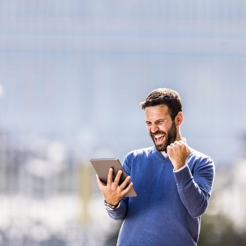 Man holding tablet and smiling in celebration