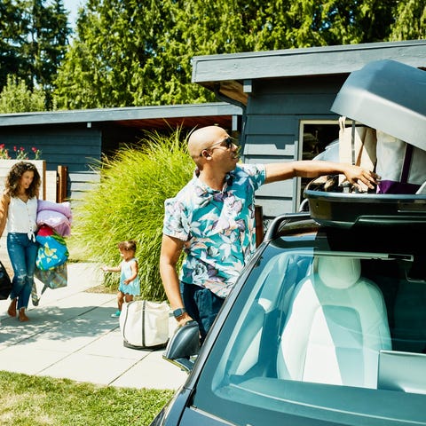 A family loads luggage into a car top carrier in p