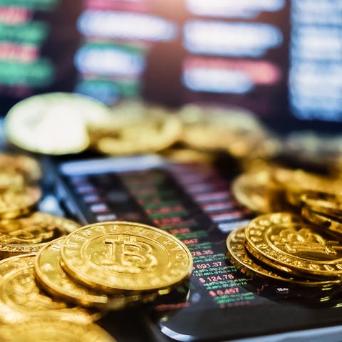 Gold-colored Bitcoin partially laid atop a smartph