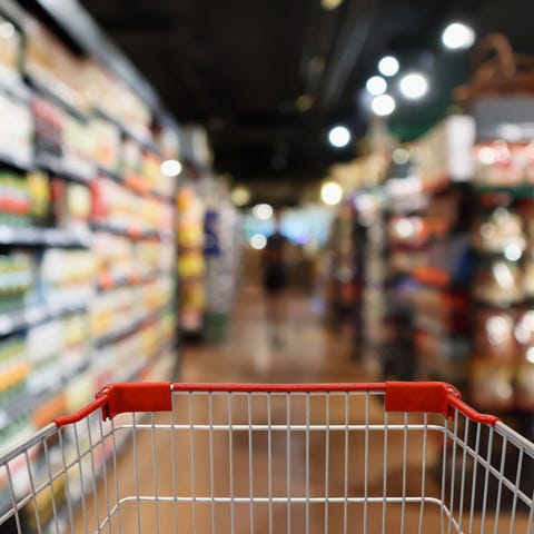 A shopping cart being pushed down a grocery aisle.