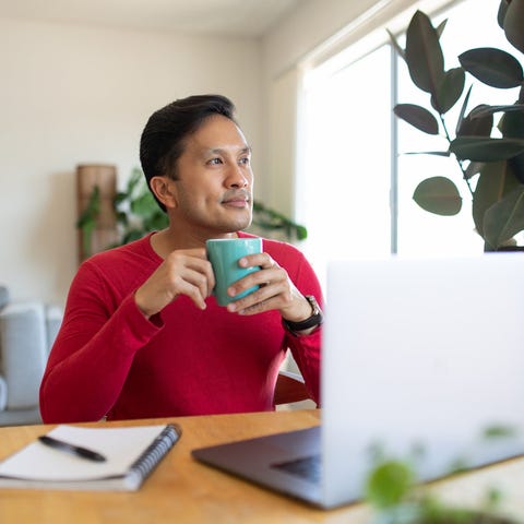 Person at laptop holding mug