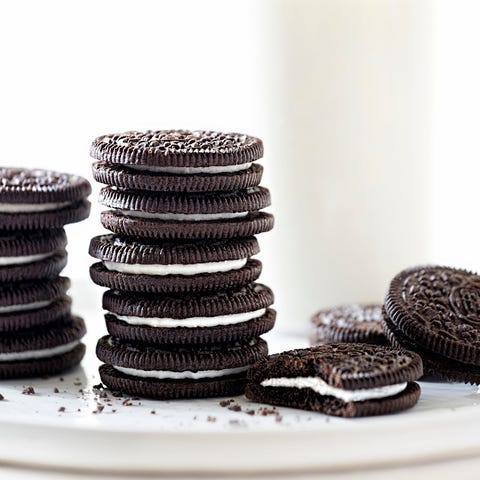 Oreo style sandwich cookies stacked on a white pla