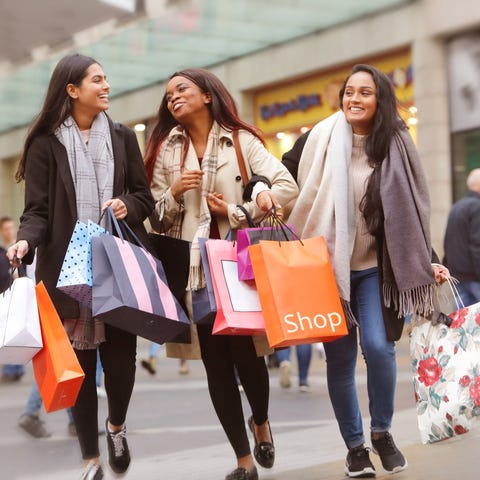 Three people walking through a mall holding shoppi