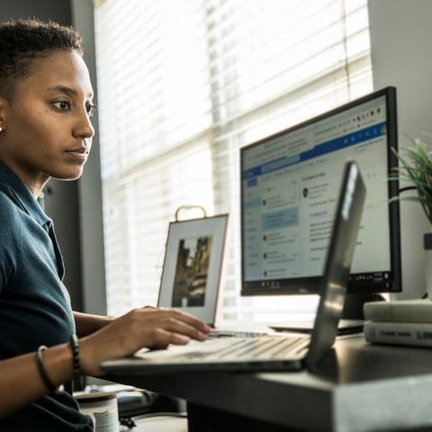 A remote worker sitting at a desk with three compu