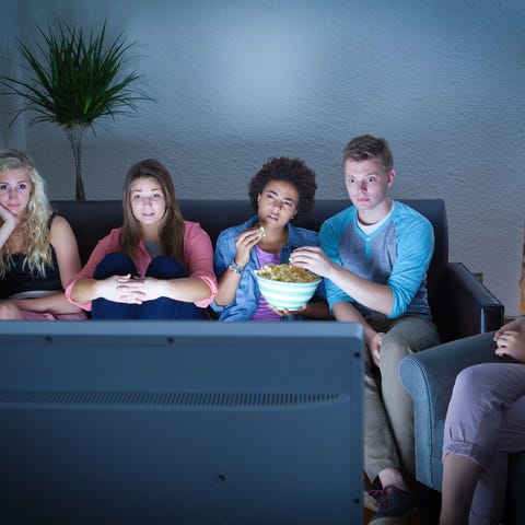 5 people sitting on couch watching TV