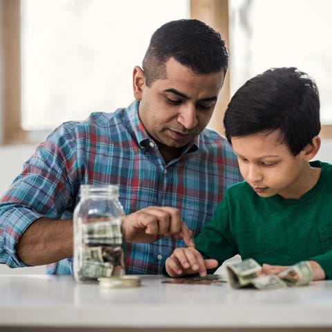 Adult and child counting money on a table.