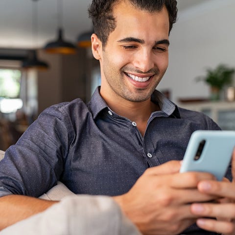 A smiling person looking at a smartphone.