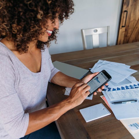 A homeowner pays bills on a smartphone at the dini