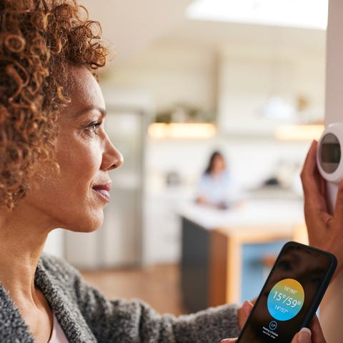 A person setting a smart thermostat in a home with