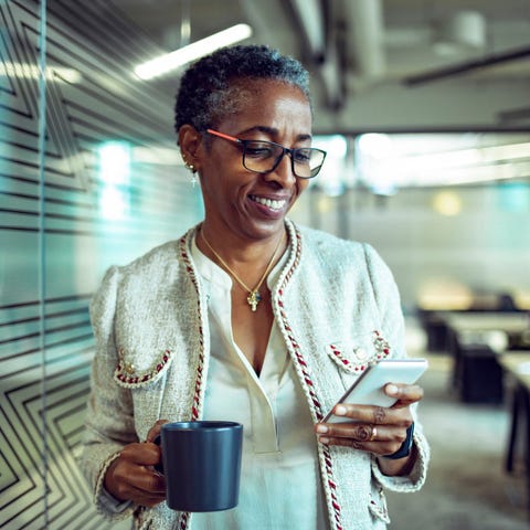 Person in office hallway, holding coffee cup and l