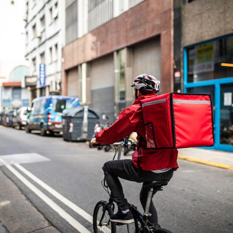 Delivery driver rides through a city with box on b