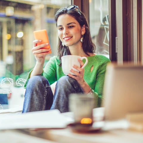 Person browsing on smartphone while sipping coffee