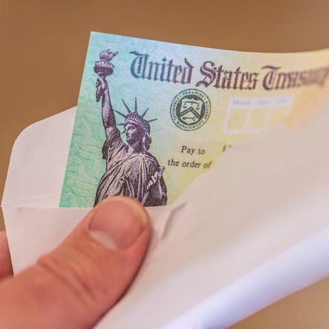 A hand holds an envelope with a Social Security ch
