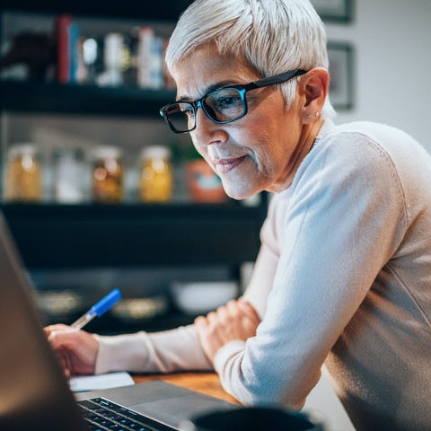 Person staring at laptop and writing note in notep