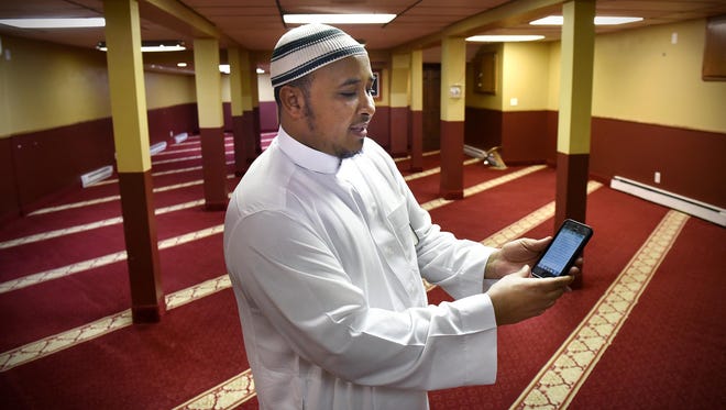 Imam Mohamed Nuh Dahir demonstrates an app he uses to read the Quran on his smartphone Thursday at the Islamic Center of St. Cloud.