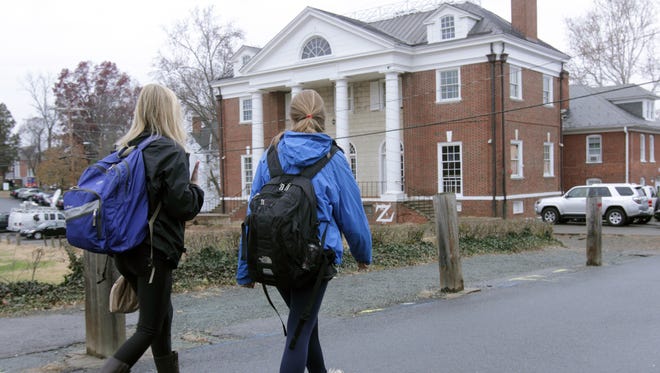 Students walk past the Phi Kappa Psi fraternity house on the University of Virginia campus.