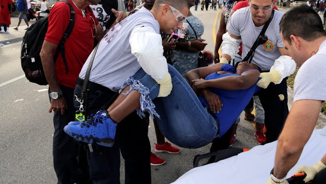 Miami-Dade Fire and Rescue paramedics lift a woman after she lost consciousness after several were injured in a shooting at Martin Luther King Jr. Memorial Park in Miami-Dade, Fla., Monday, Jan. 16, 2017. The Miami Herald reports that hundreds of people had gathered in the park after the annual MLK Day parade.