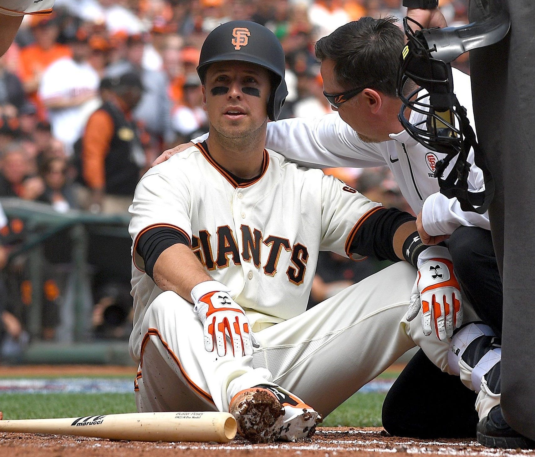 SAN FRANCISCO, CA - APRIL 10:  Buster Posey #28 of the San Francisco Giants sits on the ground and is checked on by manger Bruce Bochy #15 and trainer Dave Groeschner after Posey was hit in the head with a pitch in the bottom of the first inning at A