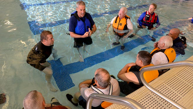 Scott Fraser, left, and Dave Robey, center, teach visually impaired kayakers and others techniques and kayaking water safety in the Outta Sight Clinic at Eaton Rapids Middle School Friday. Team River Runner is hosting the event for visually impaired kayakers to receive training in a flat water paddling environment. Guides are also participating in the clinic.