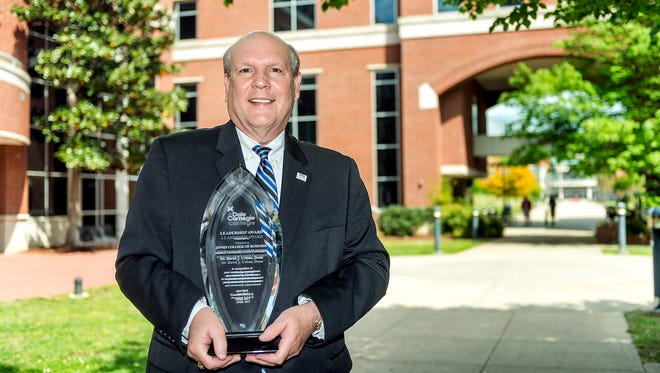 David Urban, dean of the Jennings A. Jones College of Business at MTSU, holds the Dale Carnegie Global Leadership Award in the courtyard of the Business and Aerospace Building. Joe Hart, president and CEO of Dale Carnegie Training Worldwide, presented the award to Urban earlier this spring at a meeting in Nashville.