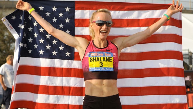 ADVANCE FOR WEEKEND EDITIONS, APRIL 17-18 - FILE - In this March 15, 2014, file photo, Shalane Flanagan holds up the American flag after setting a women's 15K record in the Gate River Run in Jacksonville, Fla. Shalane Flanagan and Desi Linden lead a group that is hoping to bring the U.S. its first women's win in the Boston Marathon since 1985. The 119th running of the Boston Marathon is Monday, April 20, 2015.  (Bob Self/Florida Times-Union via AP, File)