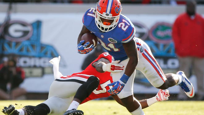 
Florida running back Kelvin Taylor (21) avoids a tackle by Georgia cornerback Damian Swann in the Gators’ 38-20 win Saturday. Taylor had 25 carries for 197 yards and two touchdowns.
