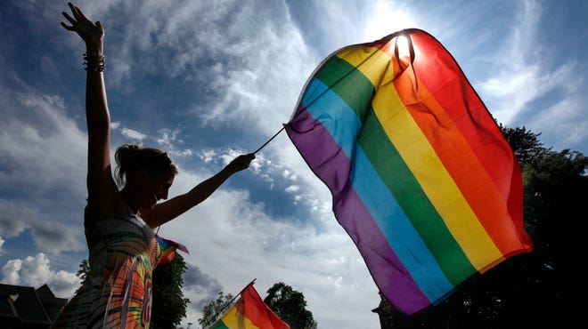 File Photo: Lesley Shephard of Rochester waves the rainbow flag as participants walk by during the 2013 Gay Pride parade on Alexander Street in Rochester.