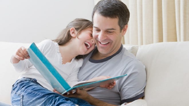 Hispanic father reading book to daughter