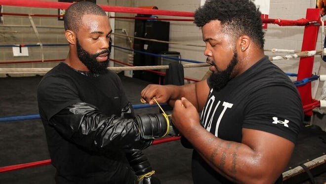 Gary Allan Russell, right, puts the gloves on his older brother, Gary Russell Jr., before a session with the mitts last week during  media workout.