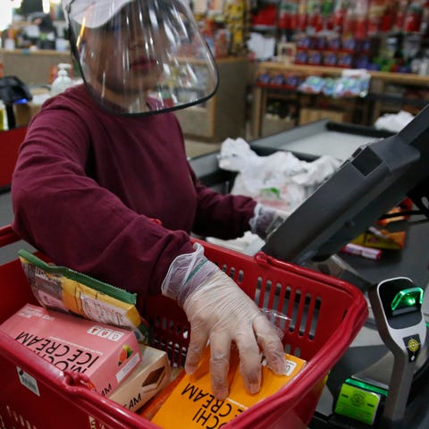 Cashier Baby San wears a face shield and gloves as