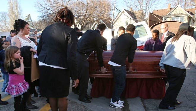 Andrea Irwin, left, looks on as her 19-year-old-son, Tony Robinson is taken away in a casket after his funeral service at Madison East High School's Milton McPike Field House in Madison.