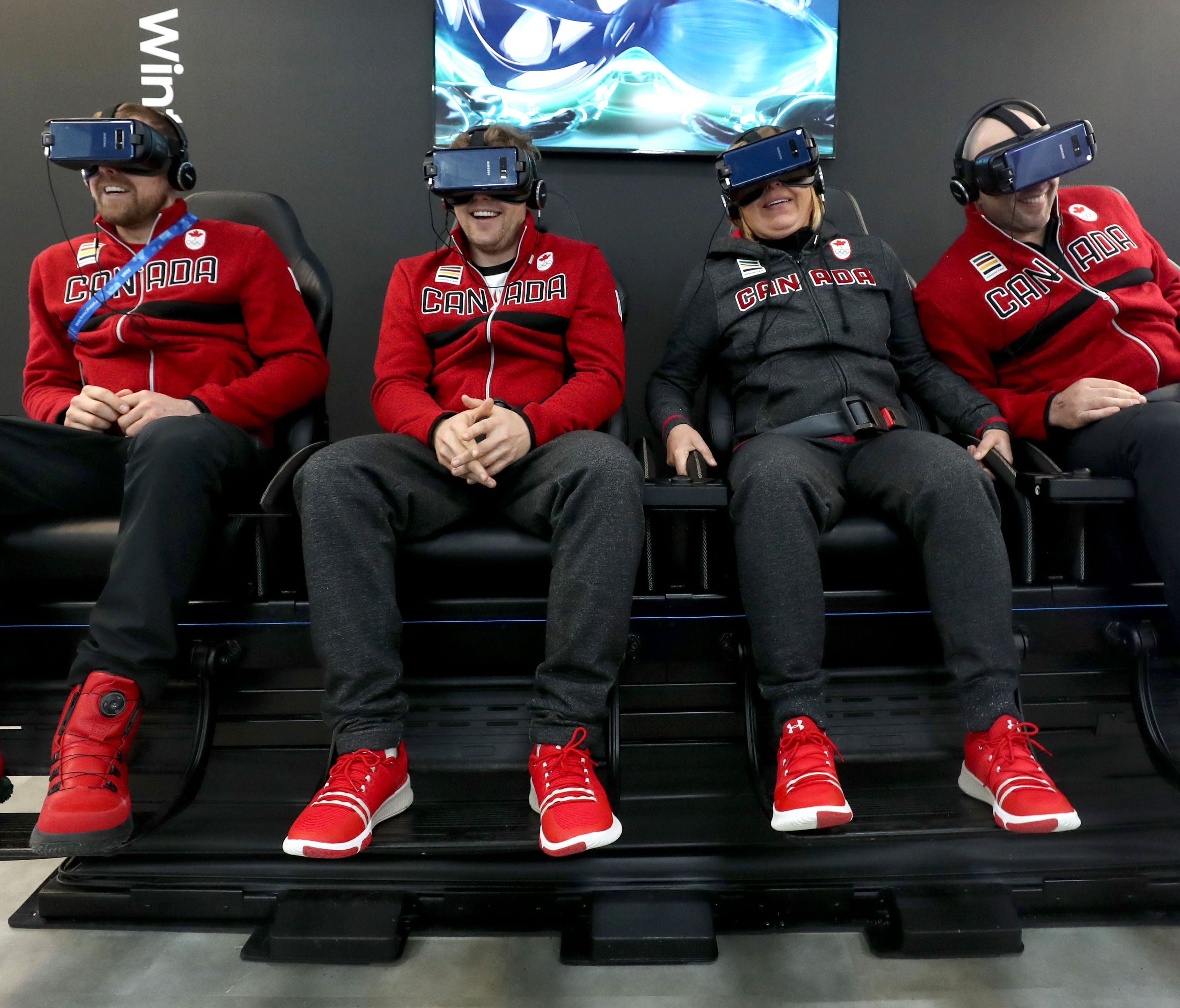 Members of Team Canada Olympic Men's Alpine skiing, Dustin Cook, left, Ben Thomsen, strength coach Agneta Platter and Manuel Osborne-Paradis, have fun on a Samsung Virtual Reality ride inside a shop located in the Plaza Zone at the Pyeongchang Olympi