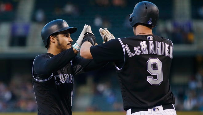 Colorado Rockies' Nolan Arenado, left, is congratulated by DJ LeMahieu as Arenado crosses home plate after hitting a two-run home run off Milwaukee Brewers starting pitcher Brent Suter during the first inning of a baseball game Friday, Sept. 30, 2016, in Denver. (AP Photo/David Zalubowski)