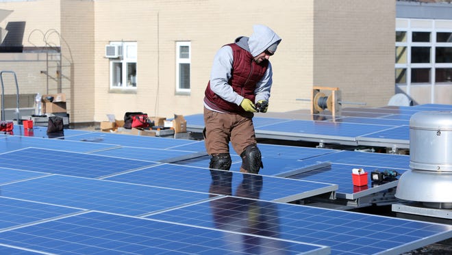 Erik Spoerle of SunBlue Energy, a Sleepy Hollow based company, installs solar panels on the roof of a Westchester Day School building in Mamaroneck.