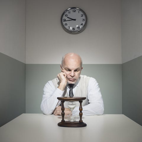 Man sitting in a small room watching an hourglass 