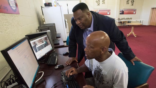 Leon Rankins III, executive director of Another Chance Transitional Services, helps client Lee Dean search for jobs on the center's computers on Wednesday, Aug. 2, 2017.