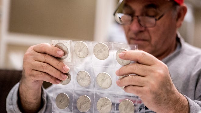 Tony Quitar, a coin collector and investor, looks through peace dollars at a private viewing of Apple Tree's safety deposit box auction later this week. 
