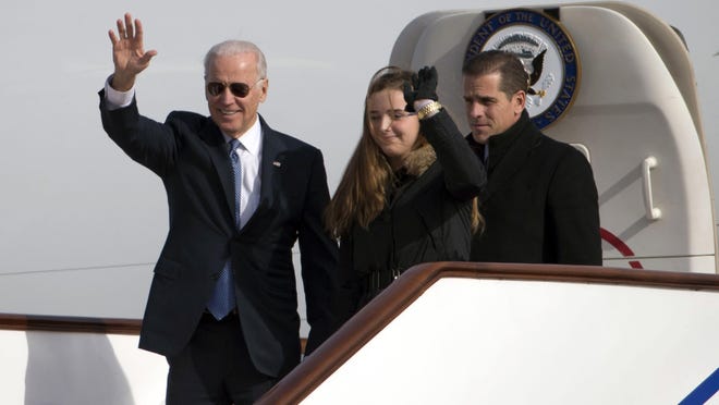 Former U.S. Vice President Joe Biden, left, waves as he walks out of Air Force Two with his granddaughter Finnegan Biden and son Hunter Biden at the airport in Beijing, China, on Dec. 4, 2013.