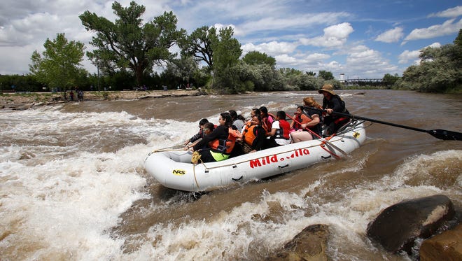 Festival goers ride a raft down the Animas River on May 23, 2015, during the Riverfest celebration in Farmington.