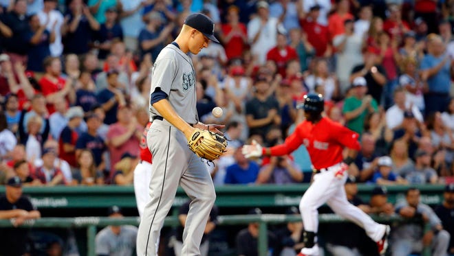 Seattle Mariners starting pitcher Mike Montgomery tosses a new ball in the air as Boston Red Sox's Rusney Castillo, right, rounds the bases after his two-run home run during the first inning of a baseball game at Fenway Park in Boston Friday, Aug. 14, 2015.