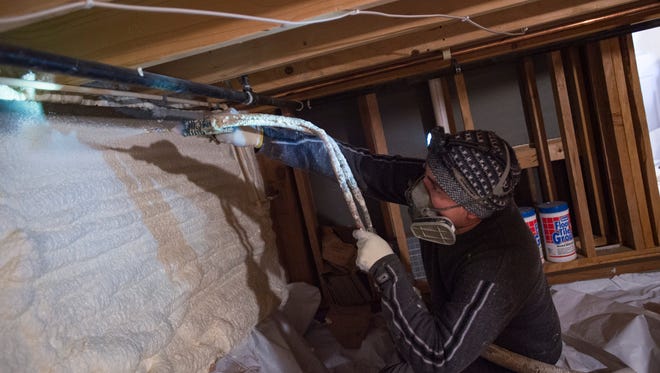 Chris Reyes of Efficiency Matters sprays foam in the lining of a crawl space in a Fort Collins home Wednesday, Dec. 21, 2016. The material provides a more energy-efficient layer to combat heating and cooling loss in the home.
