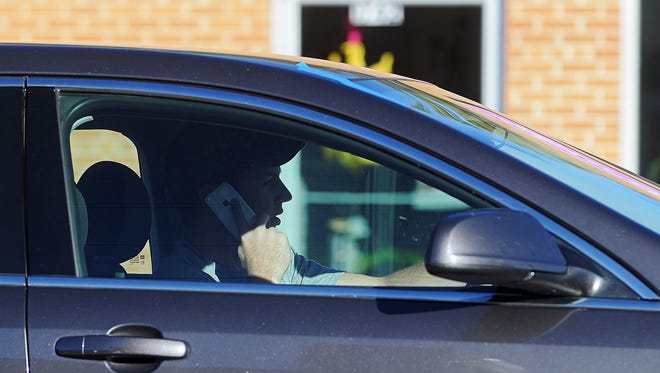 A driver uses his mobile phone while stopped at the intersection of Cliff Avenue and 26th Street Monday, Oct. 12, 2015, in Sioux Falls.