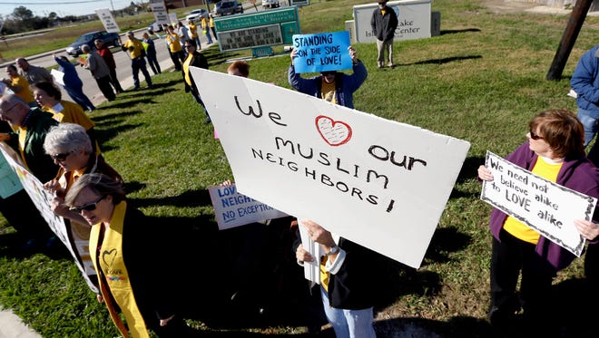 Paula Criswell, center, holds a sign as she joins others in a rally to show support for Muslim members of the community near the Clear Lake Islamic Center in Webster, Texas on Friday, Dec. 4, 2015.