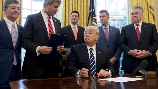 US President Donald Trump speaks with Representative Bill Huizenga (2nd L), Republican of Michigan, before signing House Joint Resolution 41, which removes some Dodd-Frank regulations on oil and gas companies, during a bill signing ceremony in the Oval Office of the White House in Washington, DC, February 14, 2017