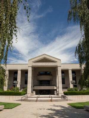 Nevada State Supreme Court building in Carson City, Nevada’s state capital. This government building is set against a dramatic blue sky and framed by trees on each side.  Applicable concepts for this image could include – justice, government, architecture, the legal system, history, bureaucracy, US capital cities, tourism, and many more.
