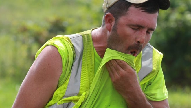 Joe Dusing of Len Riegler Blacktop wipes sweat from his face as he lays asphalt on Saddlebrook Drive in Florence. The asphalt is 300 degrees; the air where the crew was working is about 180 degrees, according to foreman Jack LaBare.