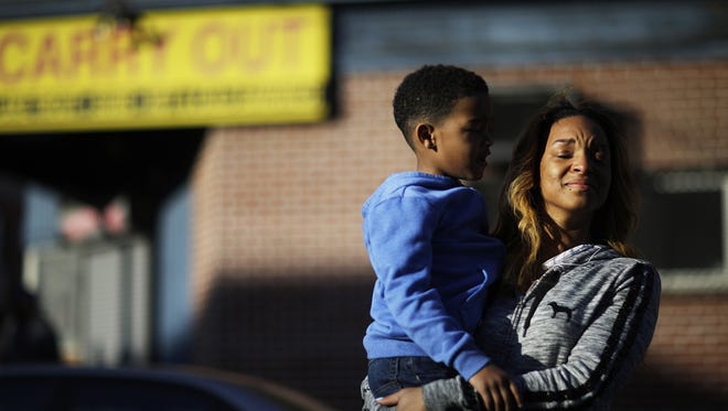 Cierra Powell fights back tears as she holds her son, Keon Lovitt, 6, as they pause to listen to an outdoor church service a block from Monday's riots that followed the funeral for Freddie Gray, who died in police custody, Tuesday, April 28, 2015, in Baltimore.